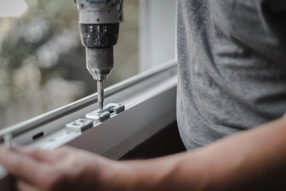 Artisan ou menuisier en discussion avec un client devant une façade résidentielle, montrant des plans ou des schémas de fenêtres et portes, illustrant l'échange personnalisé et la phase de consultation avant chantier. L'image doit mettre l'accent sur la relation de confiance et le professionnalisme, avec des matériaux de travail (plans, devis) visibles.